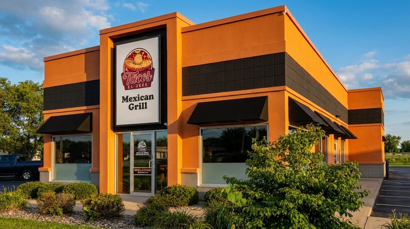 Exterior of Tacos El Jefe Mexican Grill, an orange building with black awnings and a large sign.