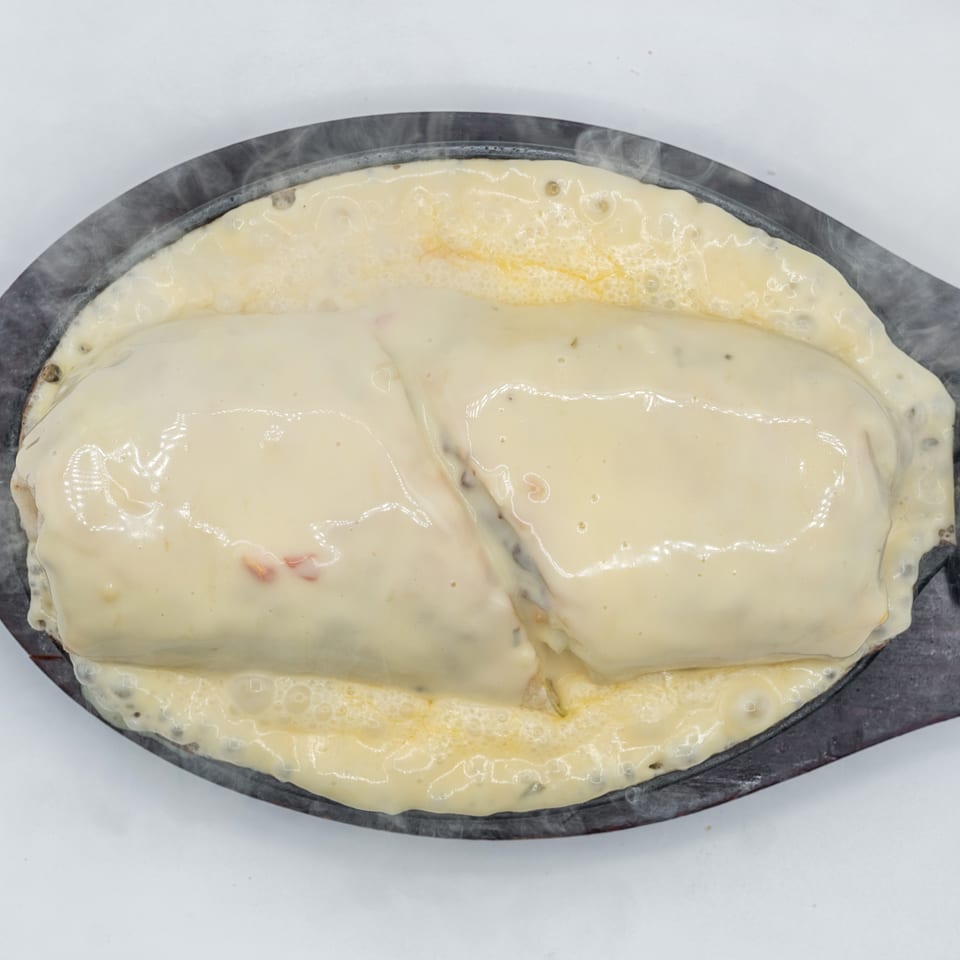 Steaming hot cheesy enchiladas on a sizzling platter, with melted cheese bubbling around the edges.